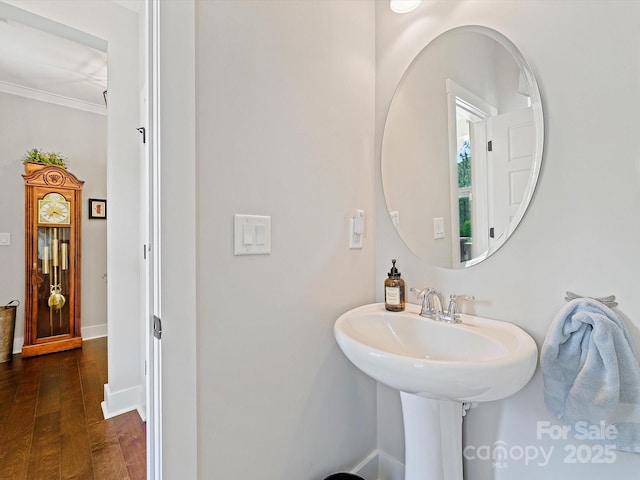 bathroom featuring wood finished floors, crown molding, and baseboards
