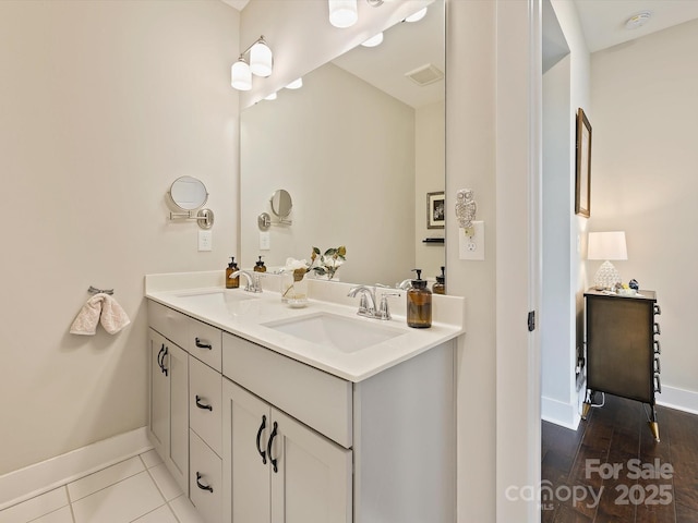 full bath with double vanity, a sink, visible vents, and baseboards