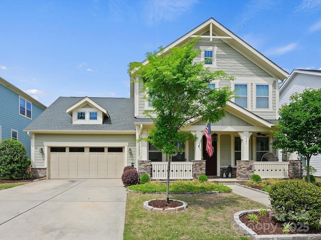 craftsman inspired home with covered porch, a shingled roof, driveway, stone siding, and an attached garage