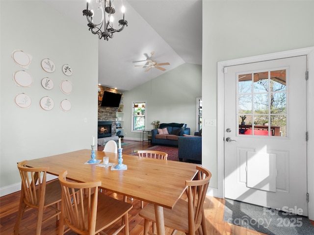 18 Birdsong Ln, Candler, NC 28715 - dining space with a stone fireplace, vaulted ceiling, ceiling fan with notable chandelier, and wood finished floors