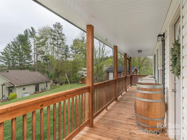 wooden deck featuring a porch and a lawn
