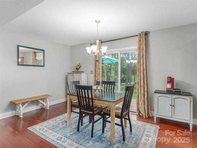 dining space featuring wood finished floors, a notable chandelier, and baseboards