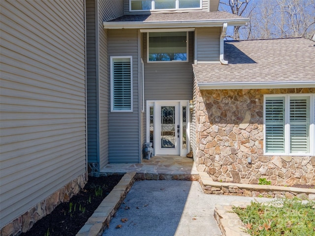 entrance to property with stone siding and roof with shingles