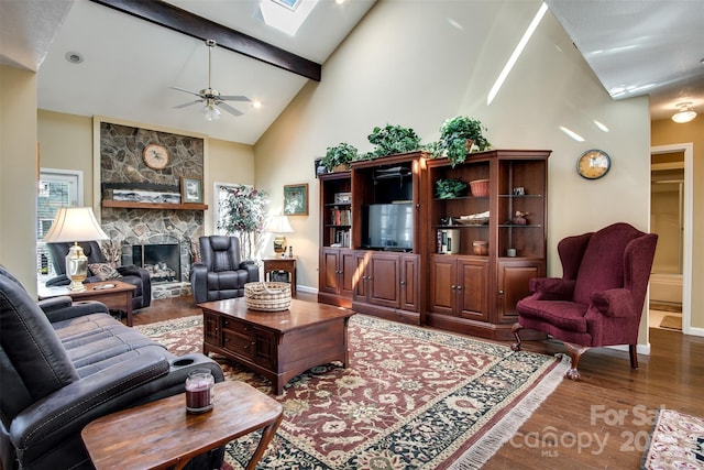 living area featuring ceiling fan, a fireplace, beamed ceiling, wood finished floors, and high vaulted ceiling