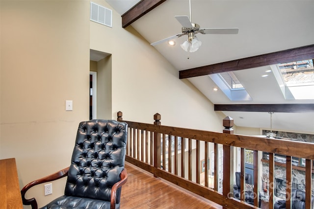 living area with a ceiling fan, visible vents, beamed ceiling, a skylight, and wood finished floors