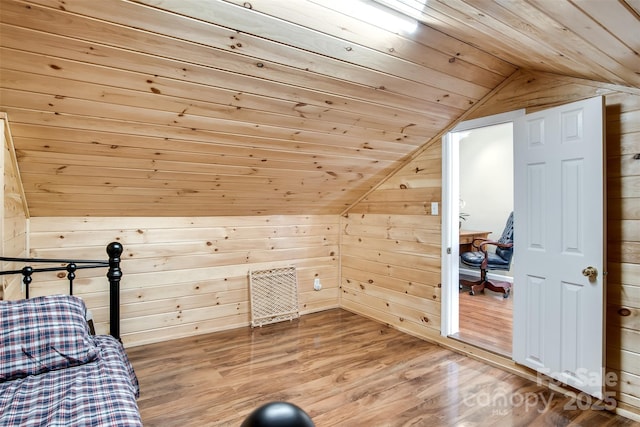 bedroom with wooden walls, wooden ceiling, wood finished floors, and lofted ceiling