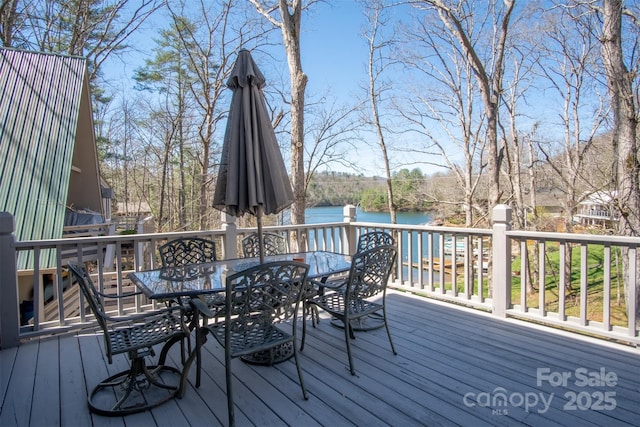 wooden terrace featuring a water view and outdoor dining space