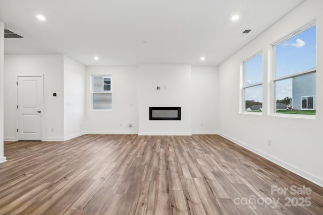 unfurnished living room featuring light wood-style flooring, baseboards, plenty of natural light, and recessed lighting