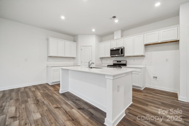 kitchen with an island with sink, white cabinetry, visible vents, dark wood-style flooring, and stainless steel appliances
