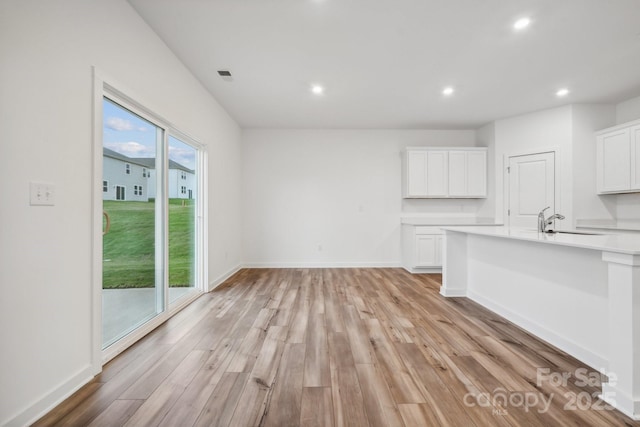 unfurnished living room with visible vents, baseboards, a sink, light wood-style floors, and recessed lighting