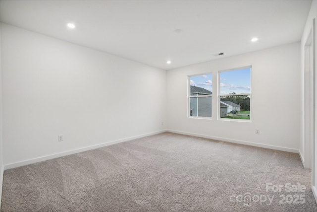 spare room with carpet floors, baseboards, recessed lighting, and visible vents
