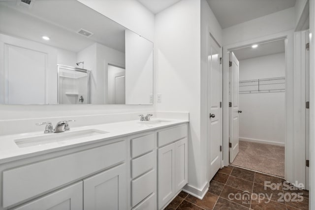 full bathroom with a shower stall, visible vents, a sink, and a walk in closet