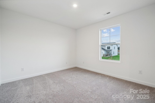 carpeted spare room featuring visible vents and baseboards