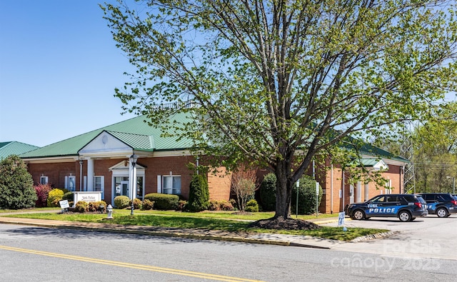 greek revival inspired property with brick siding and a front yard