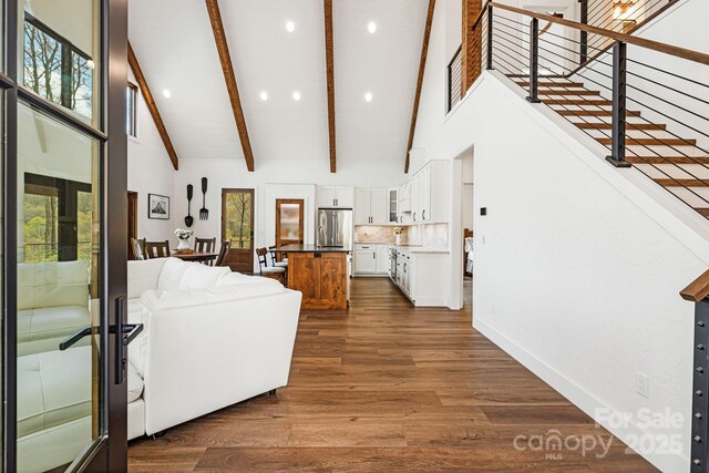 living area with stairs, beamed ceiling, recessed lighting, and high vaulted ceiling