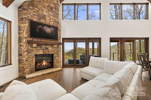 living area with baseboards, wood finished floors, a fireplace, and a healthy amount of sunlight