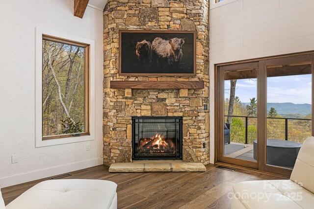 living area with a mountain view, wood finished floors, visible vents, a fireplace, and baseboards