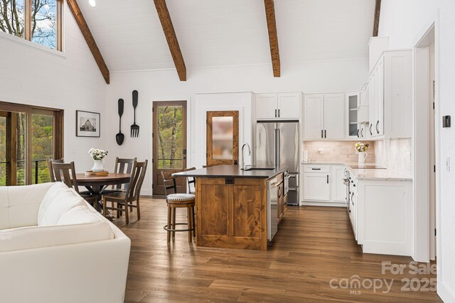 kitchen with appliances with stainless steel finishes, glass insert cabinets, dark wood-style flooring, backsplash, and beam ceiling