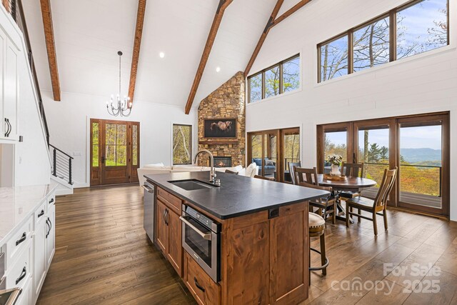 kitchen featuring a sink, beam ceiling, high vaulted ceiling, a fireplace, and stainless steel dishwasher