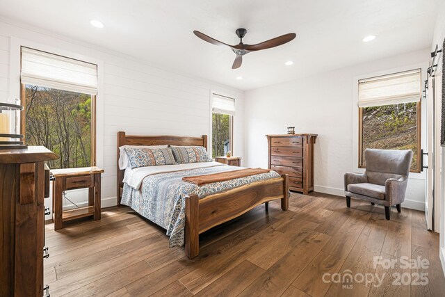 bedroom featuring recessed lighting, a barn door, ceiling fan, and wood-type flooring