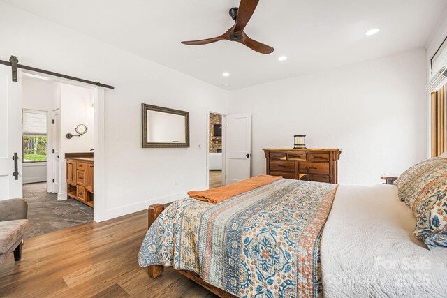 bedroom featuring wood finished floors, a barn door, baseboards, ceiling fan, and recessed lighting