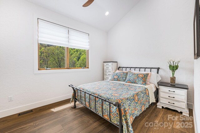 bedroom with a ceiling fan, visible vents, baseboards, dark wood-style flooring, and lofted ceiling