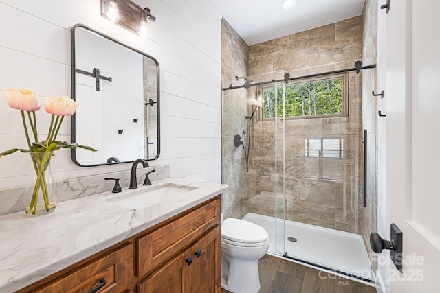 full bath with a shower stall, vanity, toilet, and wood finished floors