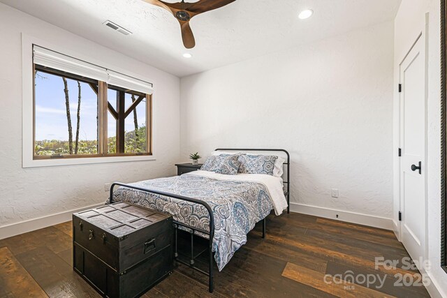 bedroom with baseboards, visible vents, and wood finished floors