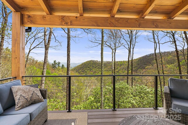 wooden terrace featuring a mountain view and a view of trees