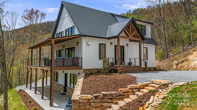 exterior space featuring roof with shingles, a patio area, and board and batten siding