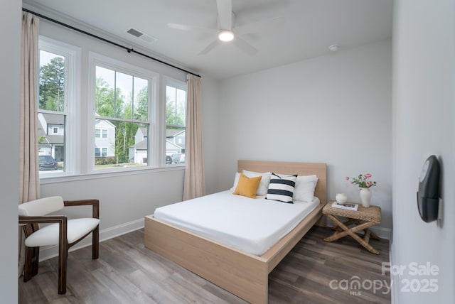 bedroom with a ceiling fan, visible vents, wood finished floors, and baseboards