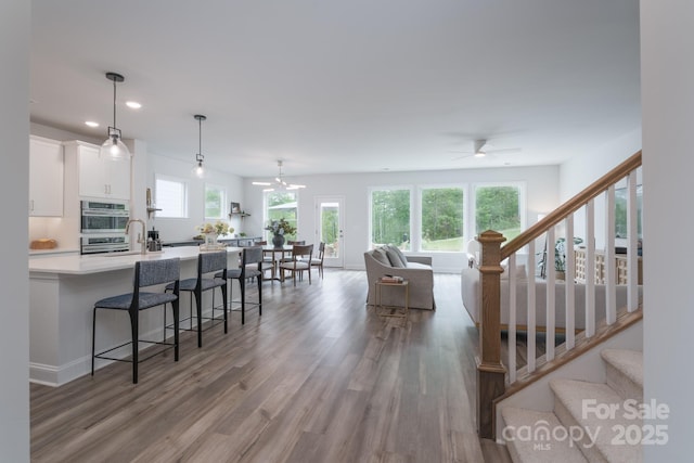 living area featuring stairway, wood finished floors, ceiling fan, and recessed lighting