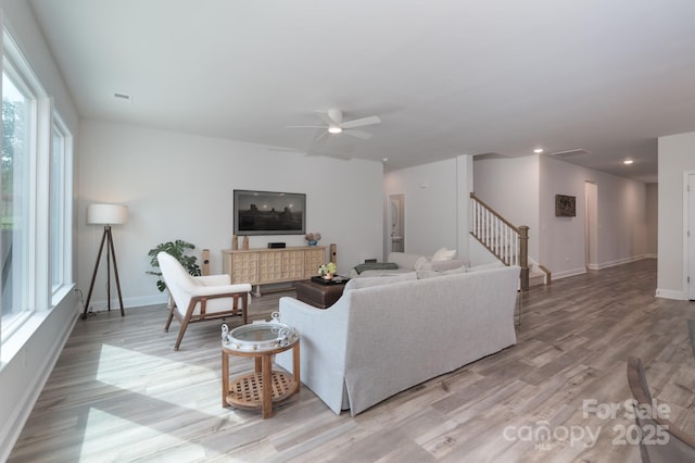 living room with light wood finished floors, ceiling fan, stairway, and plenty of natural light