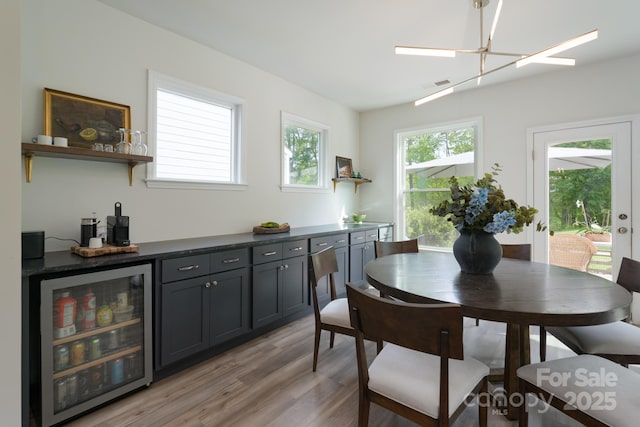 dining room featuring an inviting chandelier, a bar, wine cooler, light wood-type flooring, and visible vents