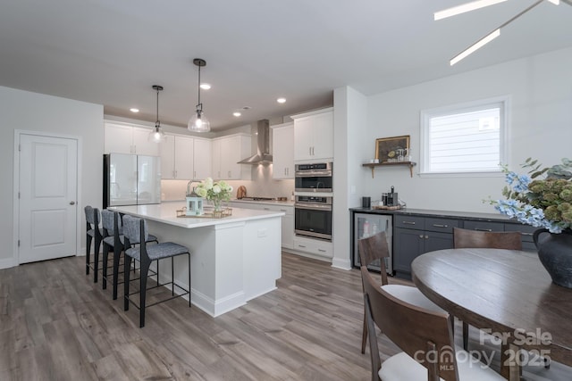 kitchen with appliances with stainless steel finishes, wood finished floors, white cabinetry, and a breakfast bar area