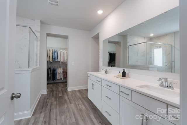 full bathroom featuring a walk in closet, a marble finish shower, and a sink