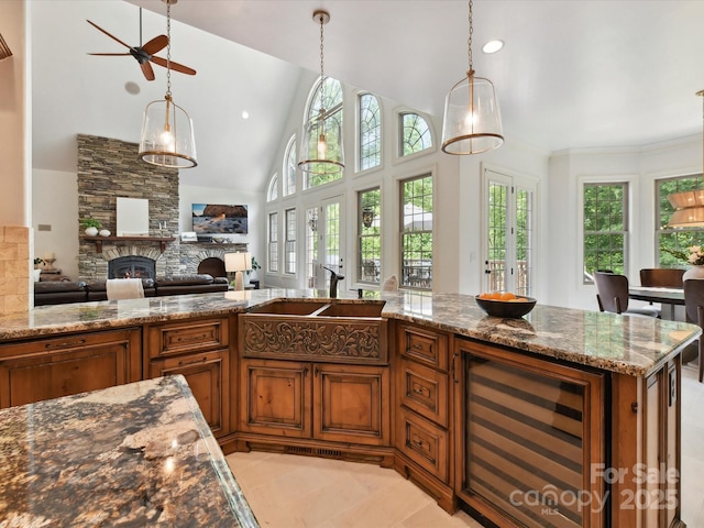 633 Elmhurst Dr, Fort Mill, SC 29715 - kitchen featuring beverage cooler, brown cabinetry, a stone fireplace, dark stone countertops, and hanging light fixtures
