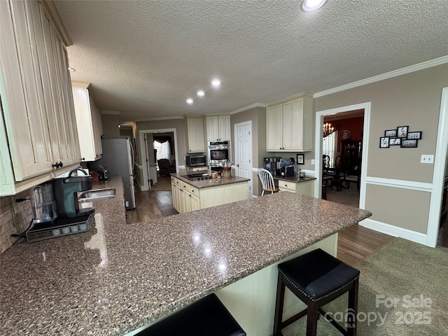 271 Ikerd Dr SE, Concord, NC 28025 - kitchen featuring ornamental molding, a peninsula, a kitchen island, dark wood finished floors, and appliances with stainless steel finishes