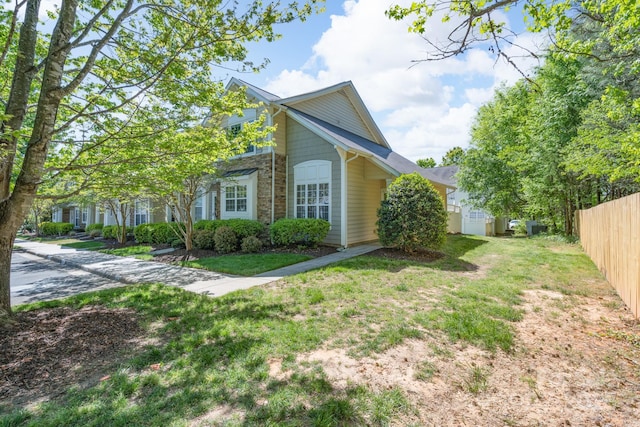 view of home's exterior with a lawn, fence, and stone siding