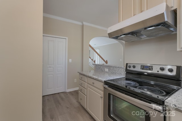 kitchen featuring under cabinet range hood, ornamental molding, arched walkways, light wood-type flooring, and stainless steel electric stove