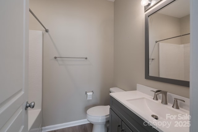 bathroom with wood finished floors, toilet, vanity, baseboards, and bathtub / shower combination
