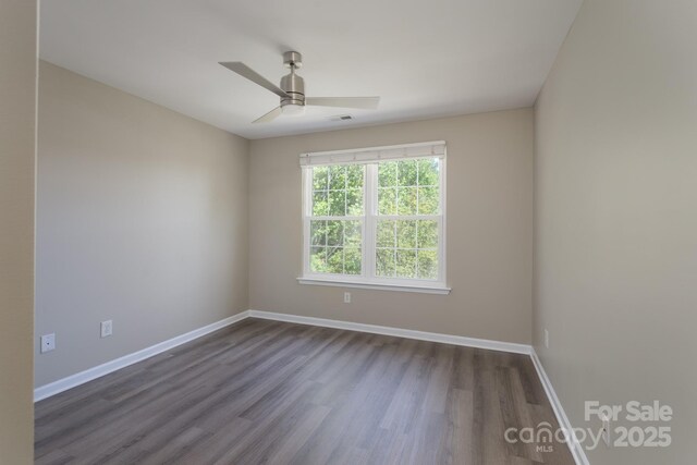 empty room featuring visible vents, baseboards, ceiling fan, and dark wood-style flooring