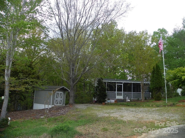 view of yard with an outdoor structure, a sunroom, and a storage unit