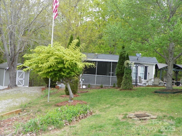 view of front of home with a shed, a front yard, a sunroom, and an outbuilding