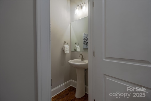 439 Beacon St NW, Concord, NC 28027 - bathroom with baseboards, a sink, and wood finished floors