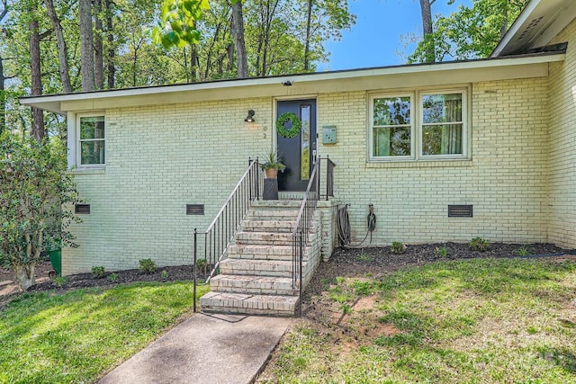ranch-style home featuring brick siding, a front lawn, and crawl space