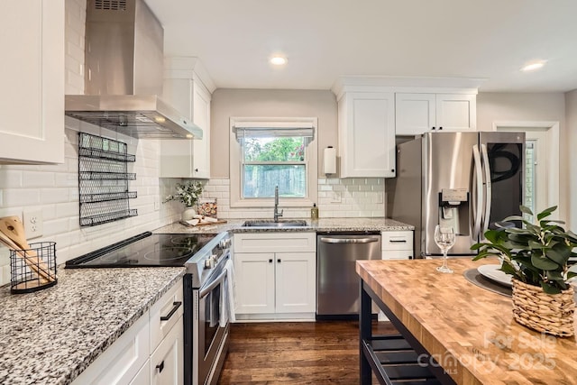 kitchen with butcher block countertops, a sink, stainless steel appliances, dark wood finished floors, and wall chimney exhaust hood