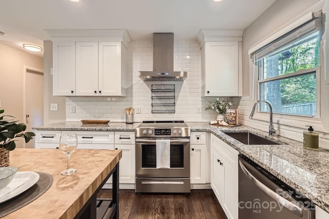 kitchen with a sink, stainless steel appliances, white cabinets, wall chimney exhaust hood, and dark wood-style flooring
