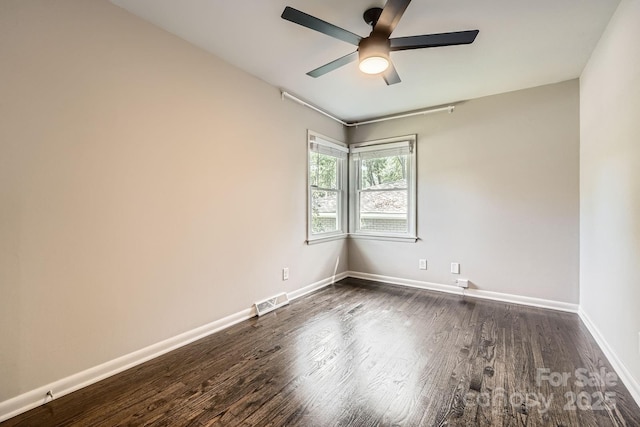 empty room with dark wood finished floors, visible vents, baseboards, and ceiling fan