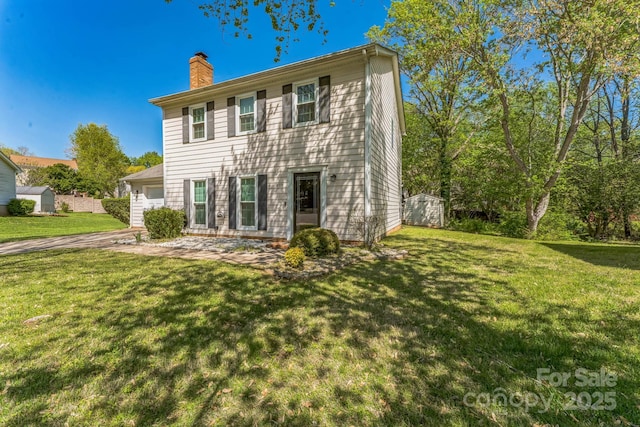 back of house featuring an outbuilding, a storage shed, a yard, an attached garage, and a chimney